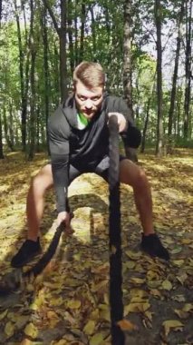 Savaş ipleri olan bir adam. Parkta halatlarla egzersiz yapan güçlü bir adam.