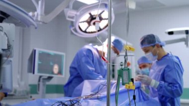 Modern bir ameliyathanede serum damlatılıyor. Beyin cerrahlarından oluşan bir ekip bulanık alanda çalışıyor..
