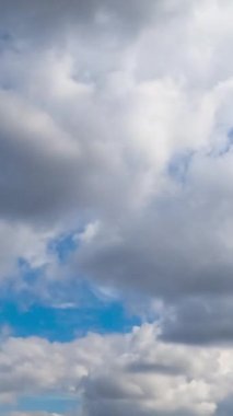 Beyaz yumuşak kümülüs bulutlarının altında uçuyorlar. Arka planda güzel mavi gökyüzü. Düşük açı. Zaman ayarlı. Dikey video