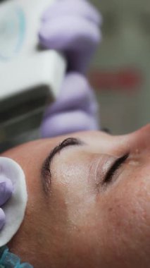 Ultrasonik yüz temizleyicisi kadın yüzünden etkilenir. Kozmetik uzmanı süngeri temizlemek için kullanıyor. Kapatın. Dikey video