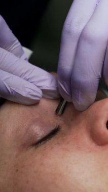 Kozmetik uzmanı cilt bakımı için metal aletler kullanıyor. Kuaförde temizlik. Kapatın. Dikey video