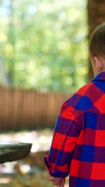 Küçük şık bir çocuk dışarıda yürüyor. Çizgili kumaş giyen çocuk oynuyor. Dikey video