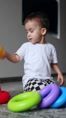 Okul öncesi eğlenceli oyun öğrenme. Küçük sevimli çocuk renkli oyuncaklarla oynuyor. Dikey video