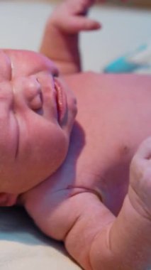 Gözleri kapalı birkaç dakikalık yeni doğan bebek doktor tarafından muayene edilmekten hoşlanmaz. Kafkasyalı bebek kontrol sırasında acı acı ağlıyor. Kapatın. Dikey video