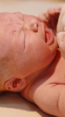 Yeni doğmuş kızıl saçlı bebek ağlarken doktorun eldivenli eli steteskopu göğsüne dayadı. Doğumdan sonra bir çocuğun hayatını kontrol etmek. Kapatın. Dikey video