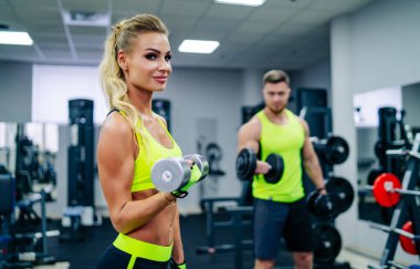 Aptal eğitim meraklıları. İki sporcu spor salonundaki dambıllarla birlikte antrenman yapıyorlar..