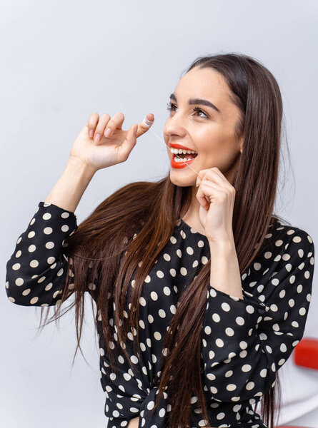 Woman with long hair plays. A woman with long brown hair and bold lipstick is playfully smiling and gesturing with her fingers.