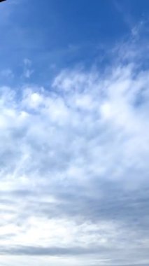 Mavi gökyüzünü gizleyen Stratus bulutları. Alçak açı kafanın üzerinden hızla geçen bulutlara bakıyor. Dikey video.