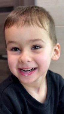 Sevimli beyaz çocuk dişlerini fırçaladı bile. Gülümseyen tatlı çocuk ağzını yıkıyor. Kapatın. Dikey video.