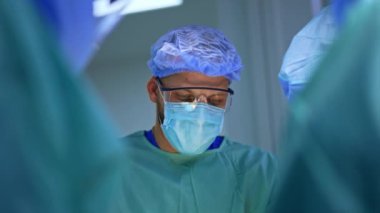 Maske, şapka ve koruyucu gözlük takan erkek doktor. Takımda çalışan bir cerrahın portresi..