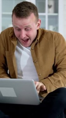 Genç adam elinde dizüstü bilgisayarla mutfak masasında oturuyor. Sinirli serbest çalışan bir adam masada oturmuş dizüstü bilgisayara bakıyor ve hızla yazarken deliye dönüyor. Dikey video