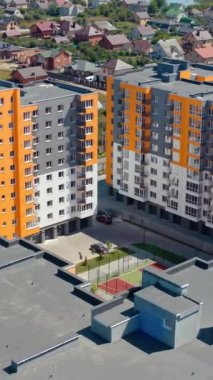 Kasabada yeni bir mimari. İkametgah inşaatı. Şehir sakinleri için modern renkli gökdelenler kompleksi. Hava görüntüsü. Dikey video