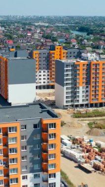 Yeni şehir kompleksi. Renkli duvarları olan uzun kentsel apartmanlar. Yeni inşa edilmiş çok katlı evleri olan bir yerleşim yeri. Hava görüntüsü. Dikey video