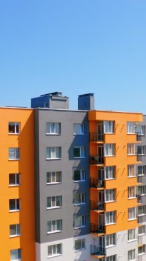 Güneşli bir günde parlak, çok katlı bir bina. Şehirdeki yüksek katlı apartmanın modern tasarımı. Mavi gökyüzü altında yaşayanlar için yeni apartmanlar. Dikey video