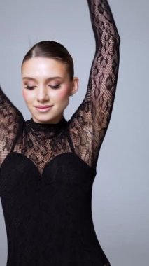 Profesyonel makyajlı çekici bir kadın dantel giyiyor. Model kameraya poz vererek ellerini kaldırır ve yüzlerine dokunur. Dikey video.
