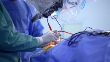 Cerrahların ellerindeki lateks eldivenler mikroskop altında elektrikli aletler kullanırlar. Doktorların ekibi beyin cerrahisi yapıyor..
