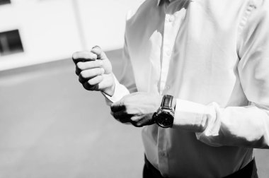 Gömlek kelepçelerini ayarlayan adam. İyi giyimli bir adam dışarıda güneşin altında dururken kelepçelerini ayarlıyor..