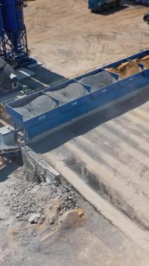 Yukarıdan asfalt fabrikasına bak. Kazıcı dışarıda çalışıyor. Modern makine kum taşır ya da kovasında ezilmiş taşlar. Dikey video