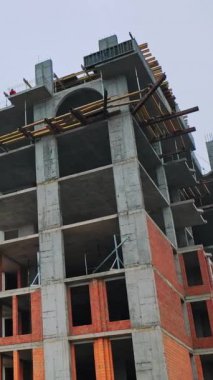 Yüksek binaların inşaatı. İnşaat sürecinde büyük bir binanın ön görüntüsü. Şehirde yeni bir inşaat alanı. Dikey video