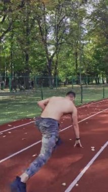 Yarış pistinde koşan sporcu. Pistte koşan atletik tişörtsüz sporcu görüntüsü