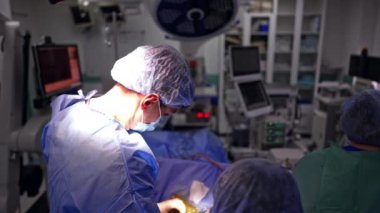 Erkek cerrah metal bir alet kullanır ve başka bir enstrüman alması için hemşireye verir. Nöroşirürji yapan tıbbi ekibin görüş açısı yüksek. Üst görünüm.