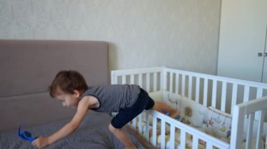 Aktif çocuk, büyük çift kişilik yataktan kalkar. Çocuk güneş gözlüğü takar ve mutlu bir şekilde atlamaya başlar..