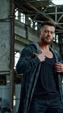 Mahvolmuş binada poz veren adam. Genç adam ayakta duruyor ve kameraya yıkıntılara karşı poz veriyor.