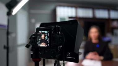 Siyah ceketli, kendine güvenen kadın bir konuşmacı video çekiyor. Bir hoparlörü kaydeden profesyonel kameranın yakın görüntüsü.