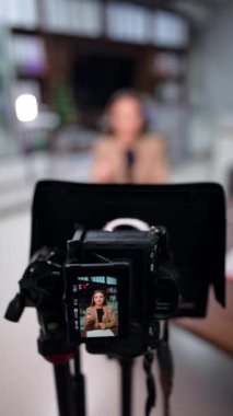 Profesyonel bir kamera tarafından çekilen pozitif beyaz kadın konuşmacı. Blog için video ya da makaralar kaydediliyor. Arkaplan bulanık. Dikey video.