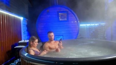 Bir çift spa 'da birlikte vakit geçirir. Beyaz adam ve kadın jakuzide oturup dinleniyorlar. Adam telefonunu kullanıyor..