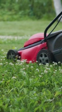 Bahçede çim biçme makinesiyle koşan küçük bir çocuk. Dikey video