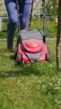 Çiftçi kadın arka bahçede çim biçiyor dikey video.