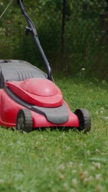 Elektrikli çim biçme makinesi çimleri keser. Çim biçen kadın. Dikey video