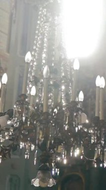 Fresklerin arka planında katolik bir katedralin ortasında lüks bir avize asılı. Kameranın hareketi yana. Dikey video