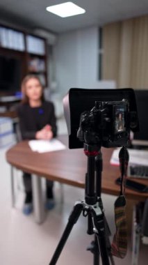 Ofiste günlük içeriği oluşturma. Tanımlanamayan esmer kadın bulanık arkaplanda kameraya konuşuyor. Dikey video.