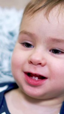 Küçük sevimli bebek yumuşak yumuşacık yastığa uzanıyor. Beyaz, şirin bir erkek bebeğin portresi. Yakından. Dikey video