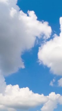 Atmosferde dönüşen güzel yumuşak bulutlar. Kümülüs bulutları parlak yaz güneşiyle aydınlanır. Düşük açı. Zaman ayarlı. Dikey video