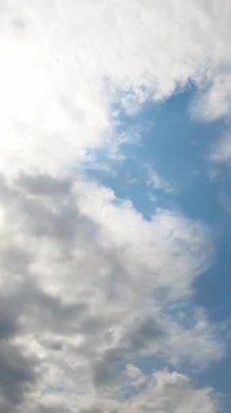 Gökyüzündeki güneş yavaşça açık gri bulutlarla kaplıdır. Dramatik bulutlar ufku kaplıyor. Düşük açı. Zaman ayarlı. Dikey video