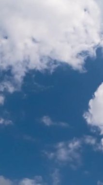 Yumuşak tüylü beyaz bulutlar gökyüzünde hızla uçuyor. Atmosferde yoğun gri bulutlar beliriyor. Düşük açı. Zaman ayarlı. Dikey video