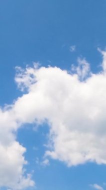 Beyaz yumuşak bulutlar griye dönüşüyor. Düşük açılı bulutlu yaz gökyüzü. Zaman ayarlı. Dikey video