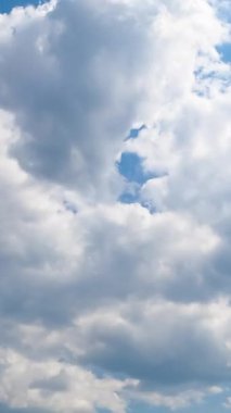 Kümülüs beyaz bulutları gökyüzünde hareket ediyor. Parlak yaz güneşinin altında yumuşak, yumuşak bulutlu bir manzara. Düşük açı. Zaman ayarlı. Dikey video