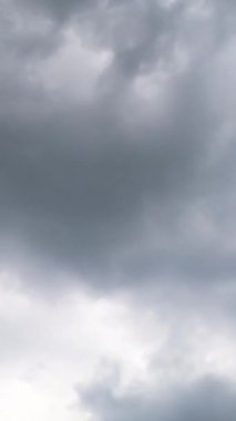 Gökyüzünü kaplayan dramatik gri bulutlar. Fırtınalı bulutlar düşük açılı görüşten birikiyor. Zaman ayarlı. Dikey video