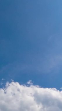 Küçük ışık bulutları rüzgarla hızlı bir şekilde uçuyor. Bulutlar gökyüzünde toplanıyor. Düşük açı. Zaman ayarlı. Dikey video