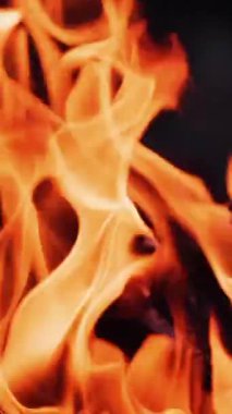 Alevlerin yavaş hareket etmesi. Güzel ateş parlak bir şekilde yanar. Turuncu alevle yanan kütükler. Yakın plan. Dikey video