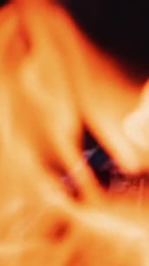 Yakın çekim bulanık parlak alev. Karanlık arka planda şenlik ateşinin canlı alevi. Sarı ve kırmızı ateşin detaylı hareketi. Ağır çekim. Dikey video