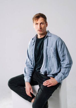 Stüdyoda kendine güvenen bir adam. Genç bir adam stüdyoda bir kaidede poz veriyor, günlük kıyafetler giyiyor ve rahat ama düşünceli bir tavır sergiliyor..