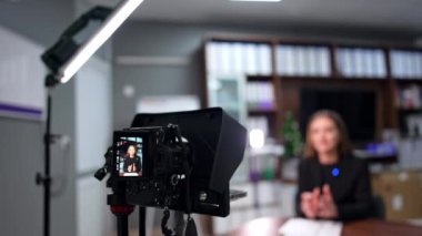 Kamera, ofiste oturan bir kadın blogcuyu kaydediyor. Kapatın. Blog ya da YouTube kanalı için profesyonel ekipman videosu.