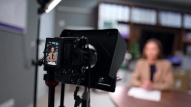 Profesyonel kameralı tripodlu bir kadın konuşmasını kaydediyor. Kapatın. Günlük oluşturma. Bulanık arkaplan.