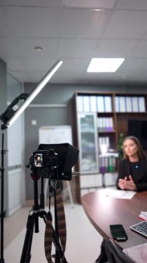 Ofiste oturup video kaydeden güzel bir kadın. Eğitici blog için pedagog film içeriği. Dikey video.