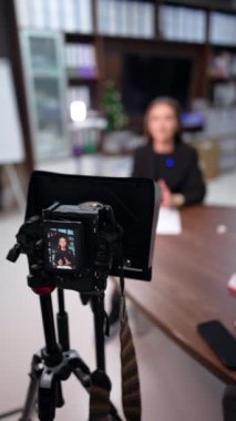 Masasında oturan beyaz bir esmeri filme alan profesyonel bir kamera. Kapatın. İnternet günlüğü için içerik oluşturma. Dikey video.